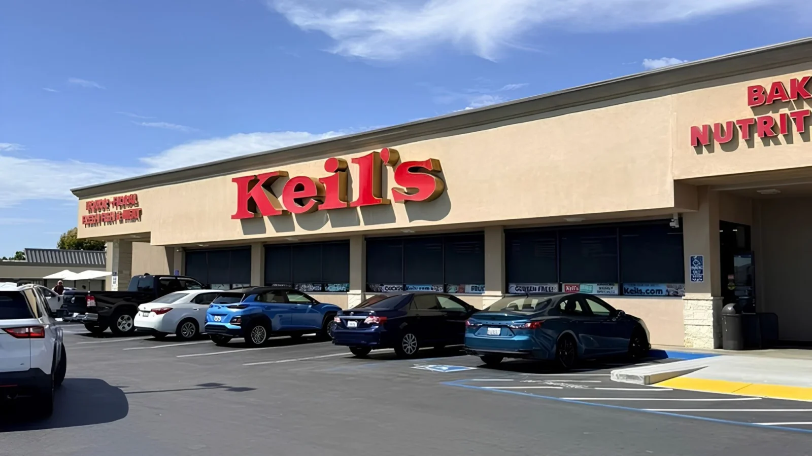 Front of Keil's Fresh Food Store with the red Keil's sign and a full parking lot on a sunny day